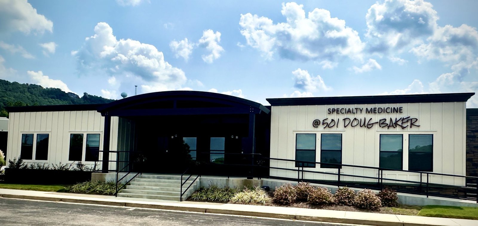The Hoover office: a white board-and-batten building with a dark curved entry canopy, signed Specialty Medicine at 501 Doug Baker, with a ramp and steps up to the front doors.